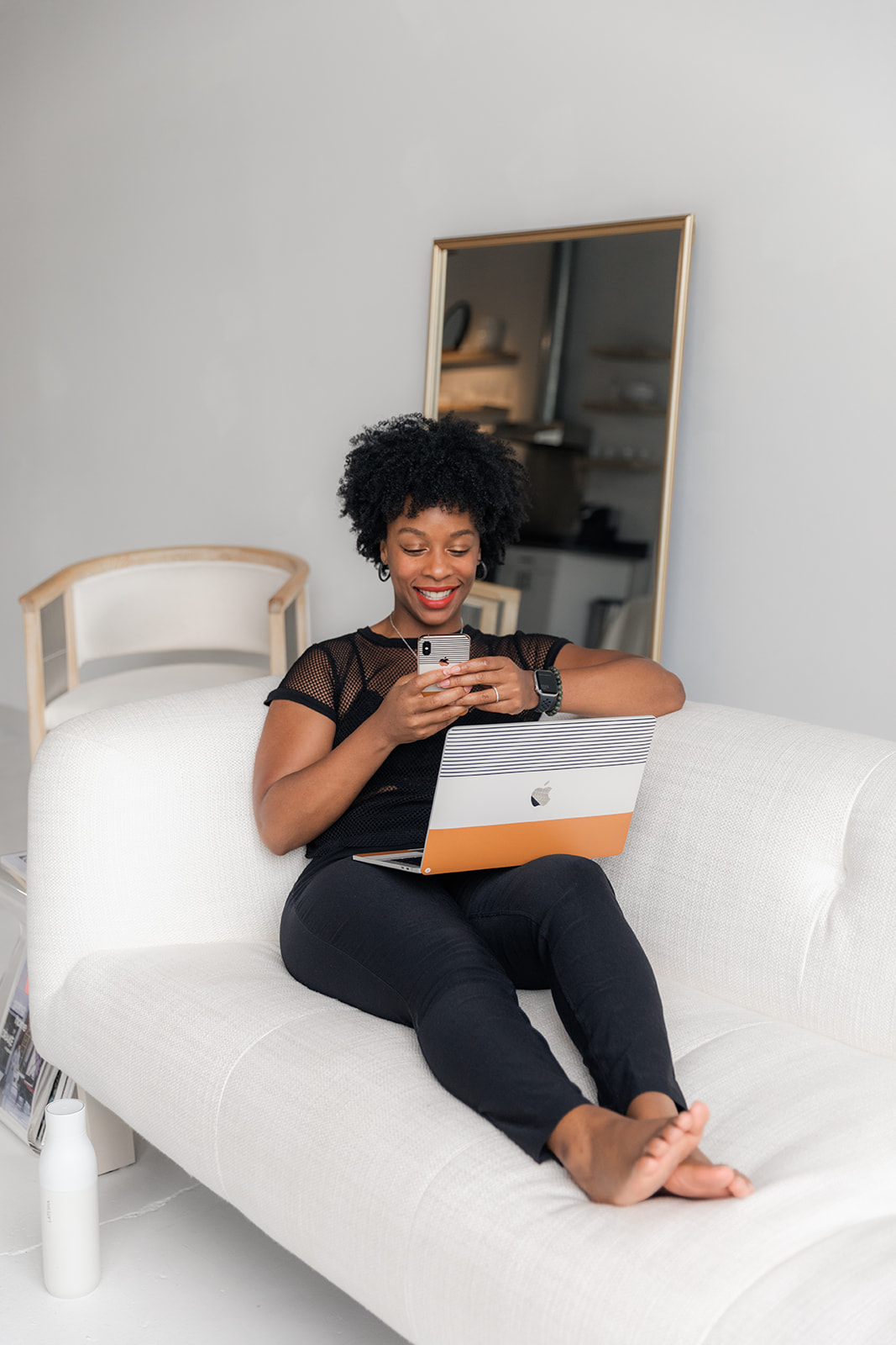 Photo of a black woman sitting on a chair writing in an agenda with a laptop sitting next to her